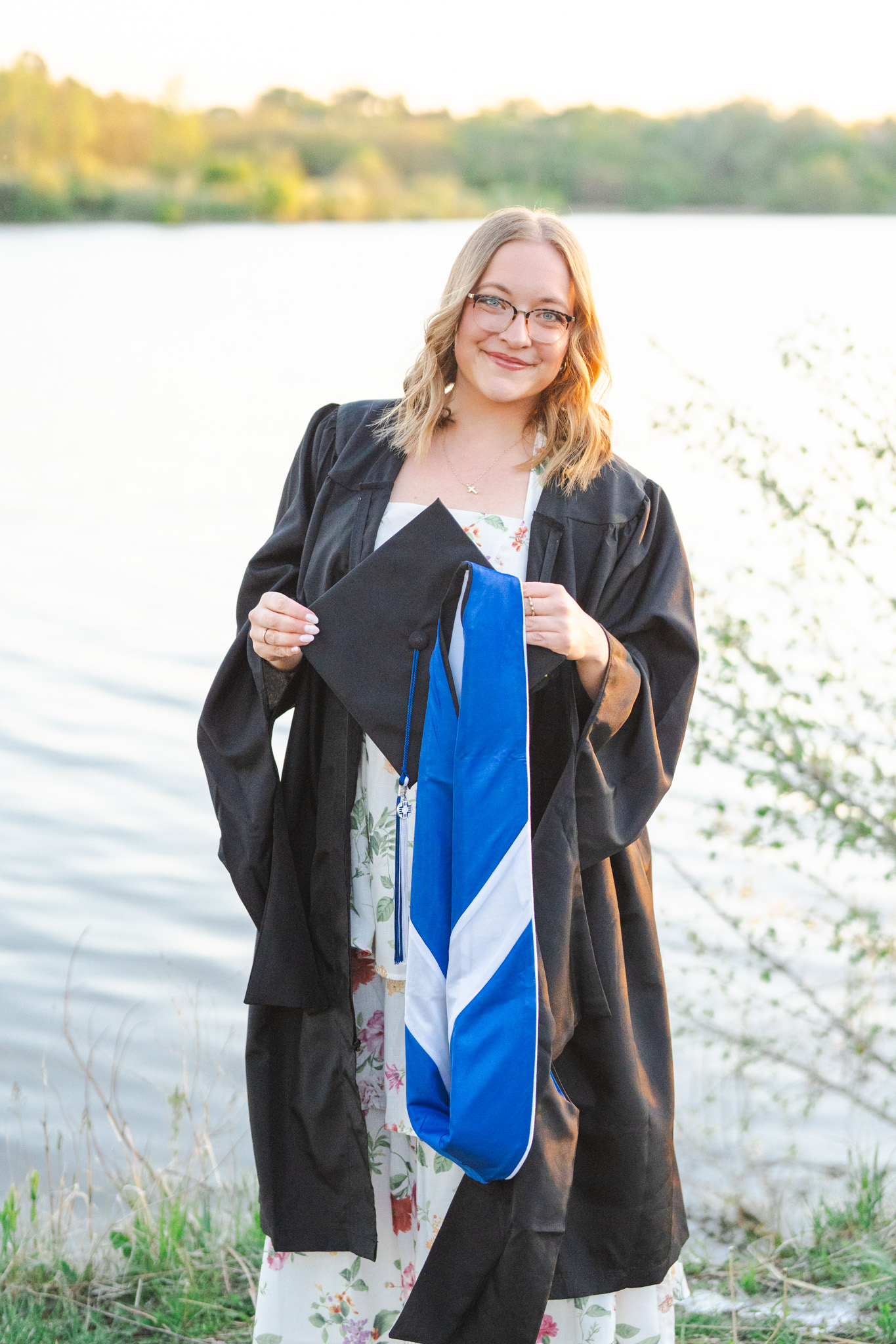 Omaha senior portrait — graduate in cap and gown by the lake at golden hour