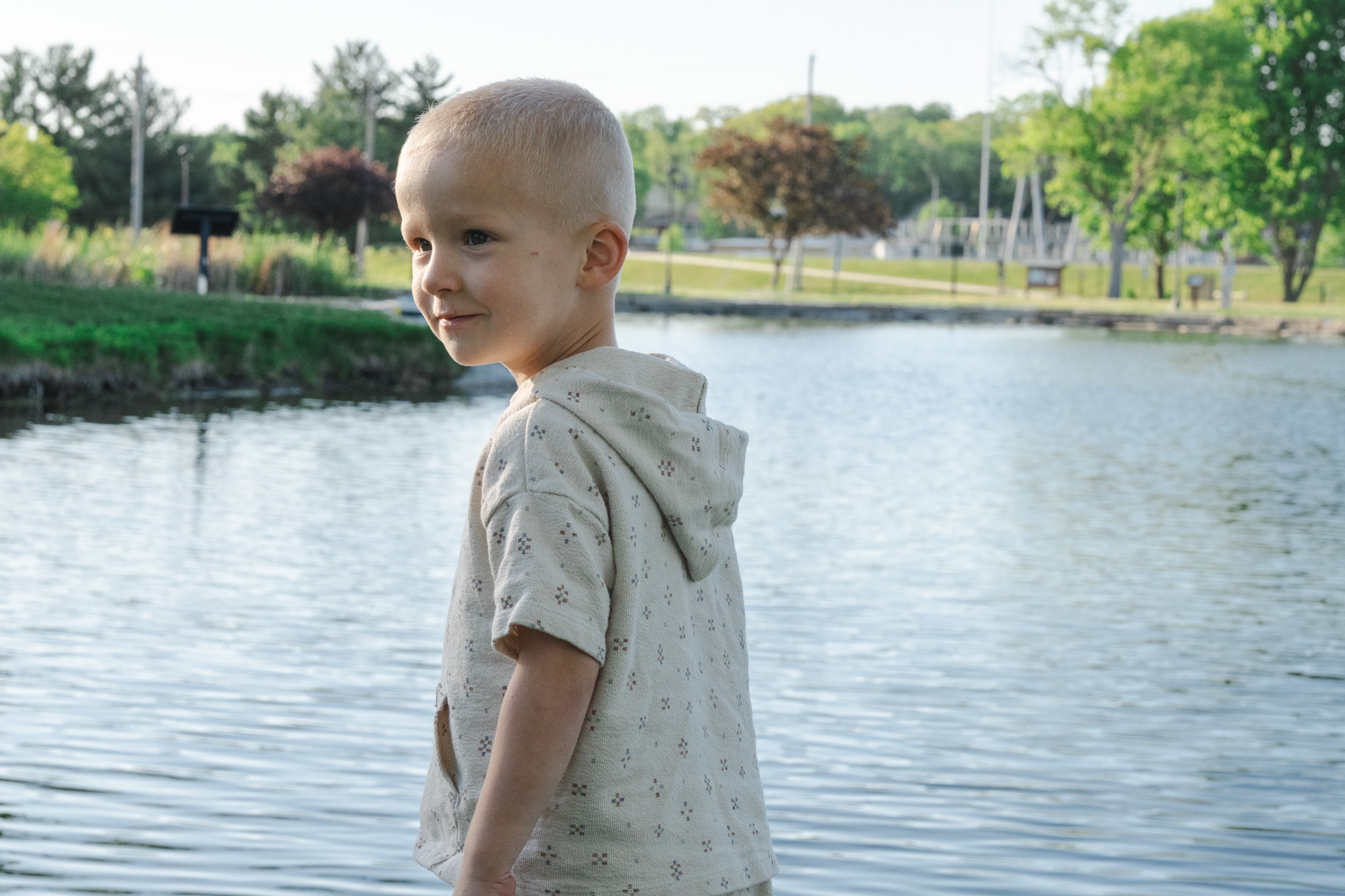 Omaha family photography — little boy glancing back by the lake at golden hour
